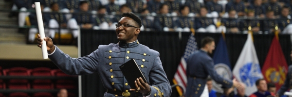 Cadet raises diploma towards a cheering crowd in Cameron Hall at ϲ during Commencement.